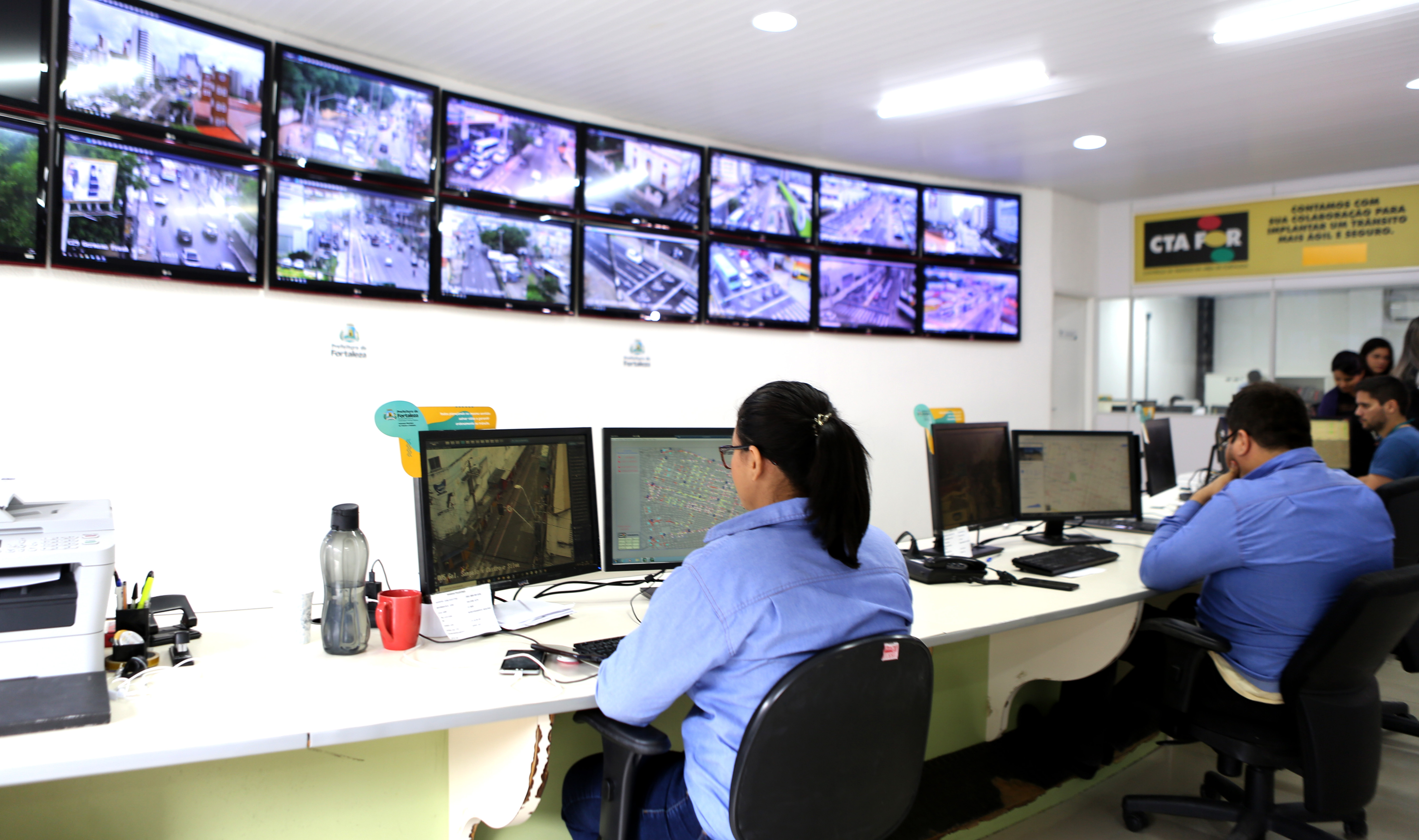 controladores de trânsito sentados olhando para vários monitores com imagens de tráfego